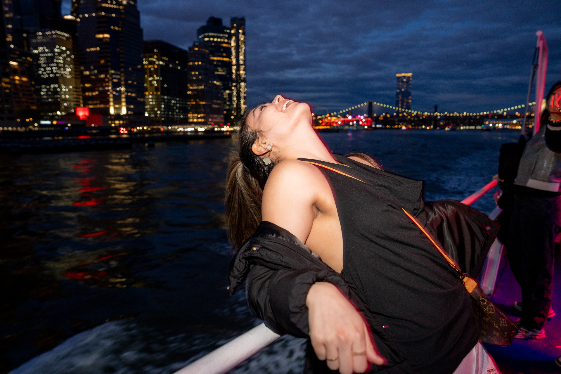 Guest leaning back laughing with Manhattan skyline at night