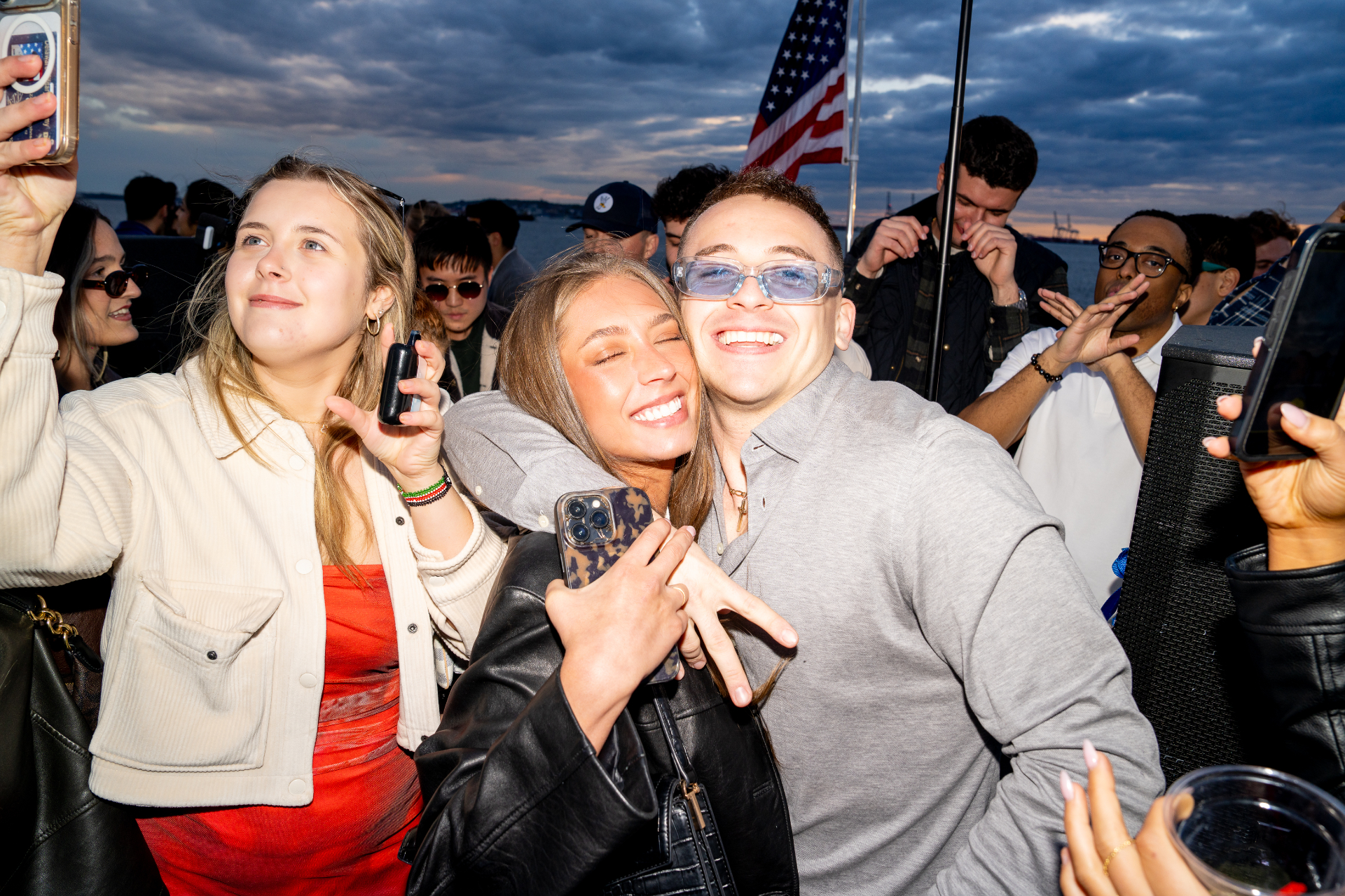 Friends celebrating on the top deck at sunset with American flag